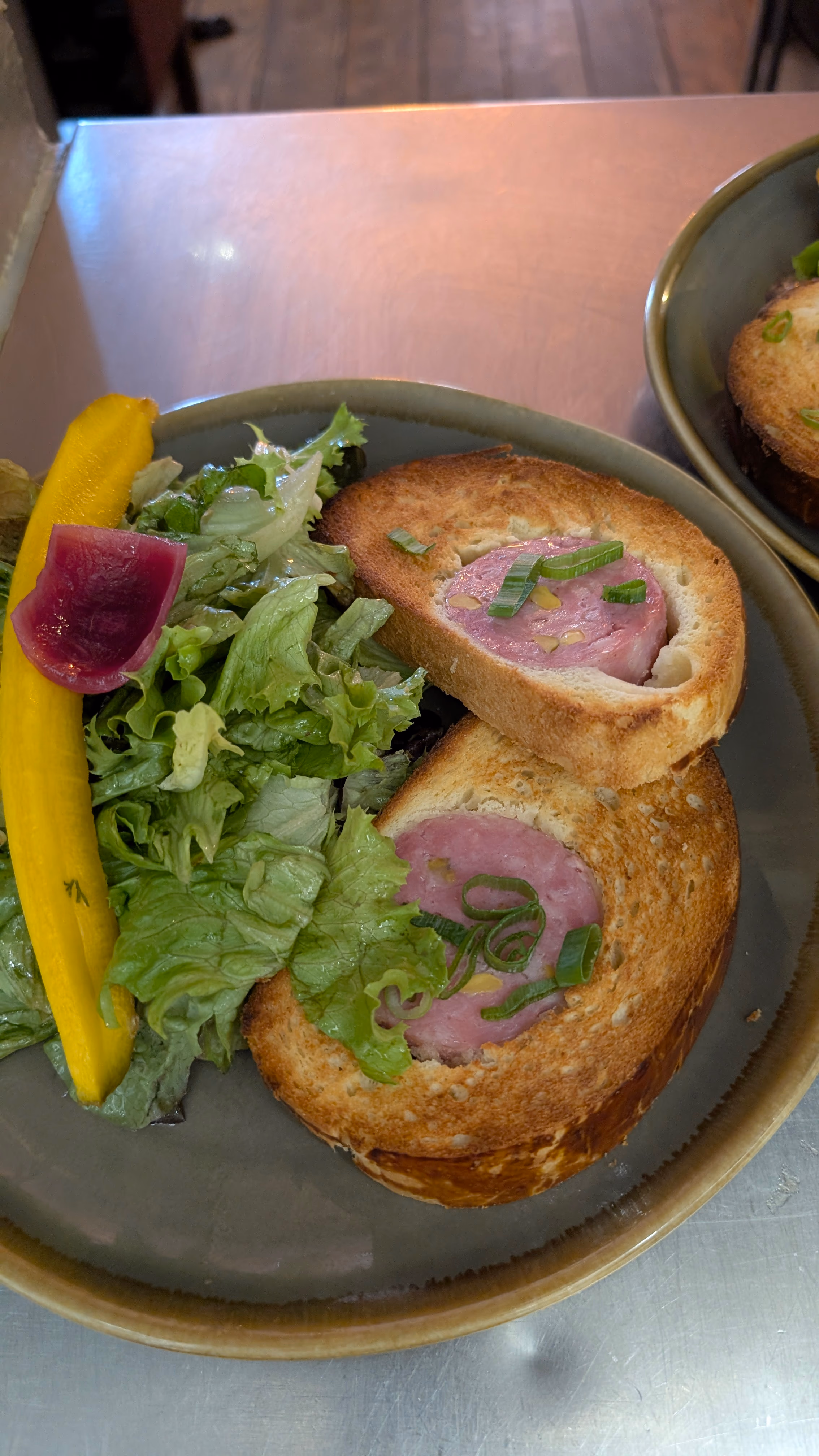 Saucisson brioché tranché servi avec une salade verte à l'Auberge des Canuts
